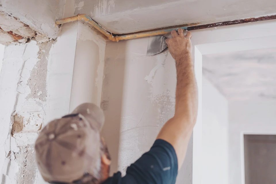 Plasterer utilisant une torche de finition pour lisser un nouveau pl&acirc;tre &agrave; la surface d'un mur &agrave; l'int&eacute;rieur d'une maison pendant les travaux de r&eacute;novation ou de construction