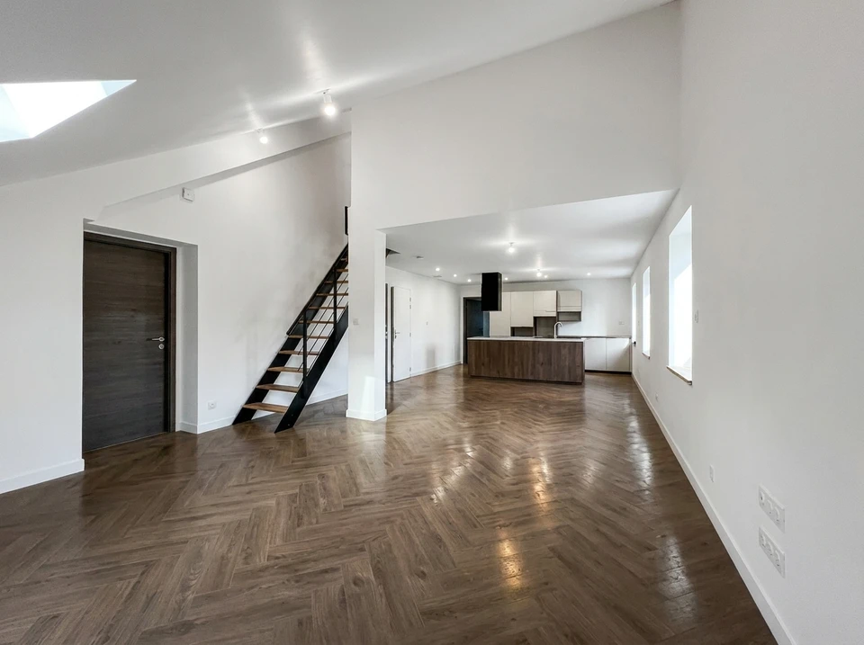 Intérieur minimaliste moderne avec mur en béton brut apparent, plancher en bois blanc, plante verte en bac rectangulaire et lampadaire contemporain blanc