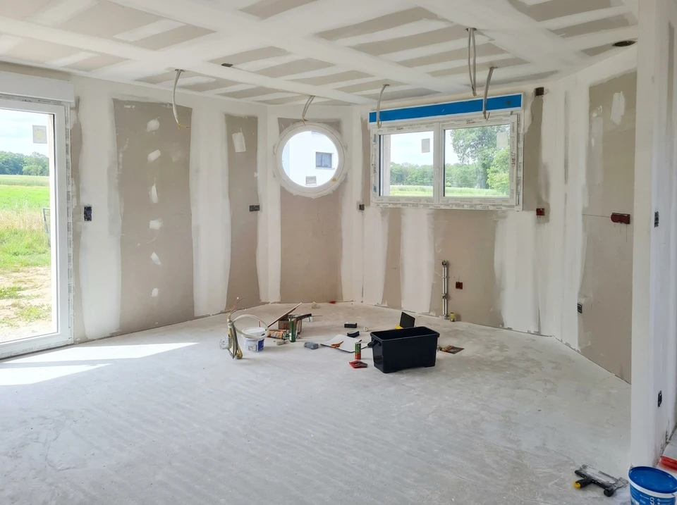 Personne appliquant de la peinture blanche sur un mur int&eacute;rieur avec un pinceau plat